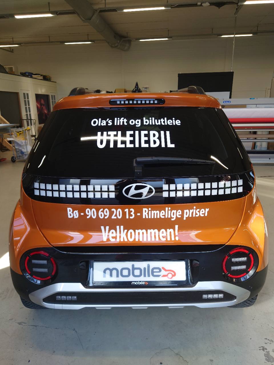 Bakside av oransje Hyundai med dekor for Ola’s lift og bilutleie